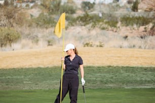 a woman holding a yellow flag on a golf course