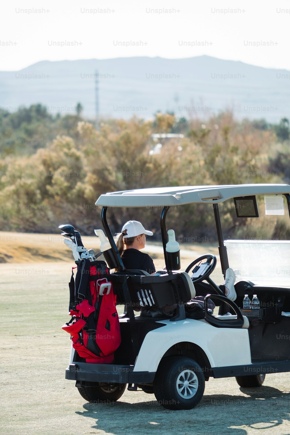 Un hombre conduciendo un carrito de golf con una bolsa de golf en la espalda