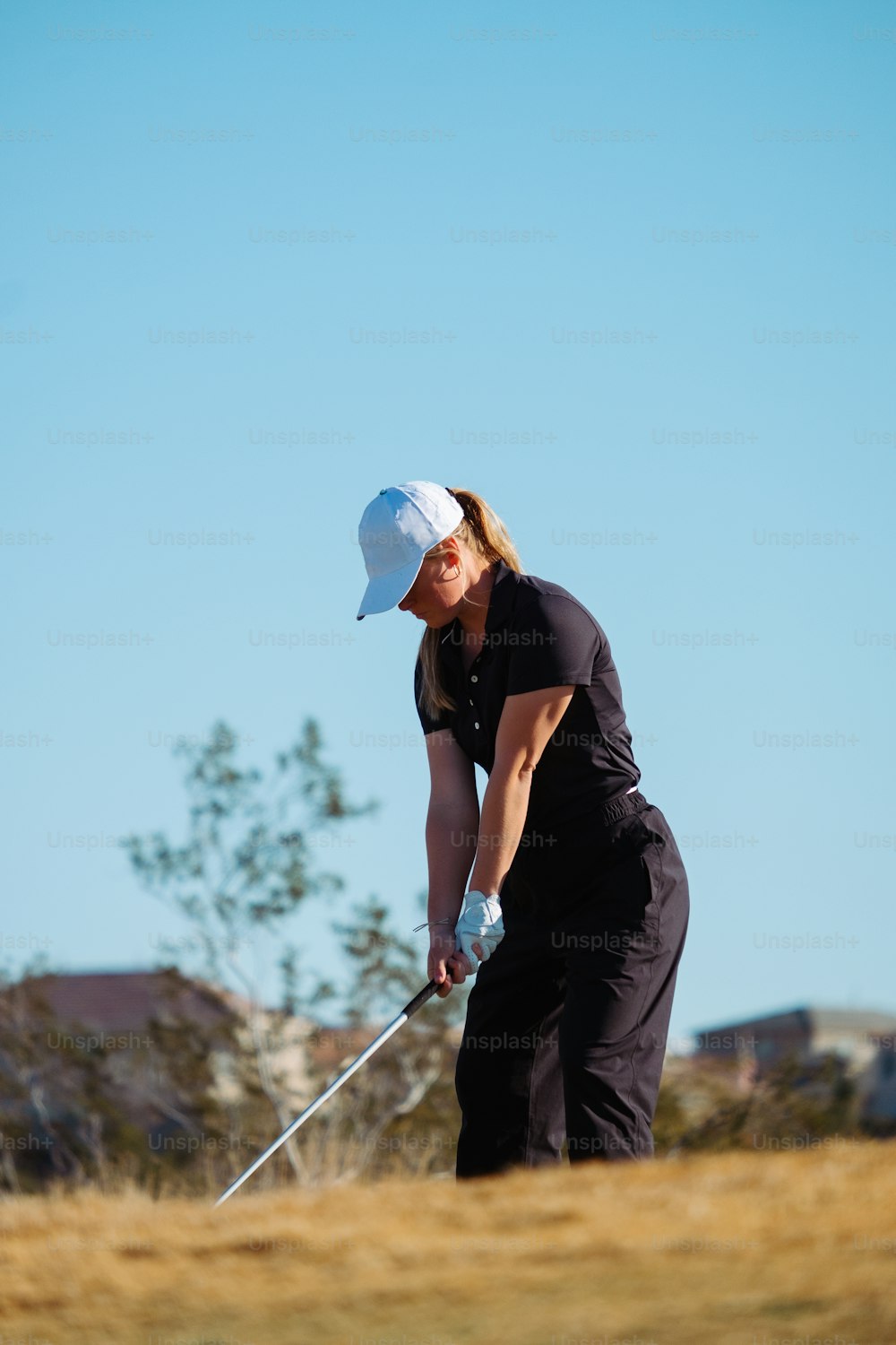 a woman in black shirt and white hat playing golf