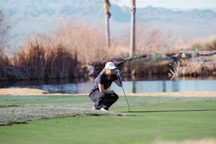 a woman kneeling down to put a golf ball on the green