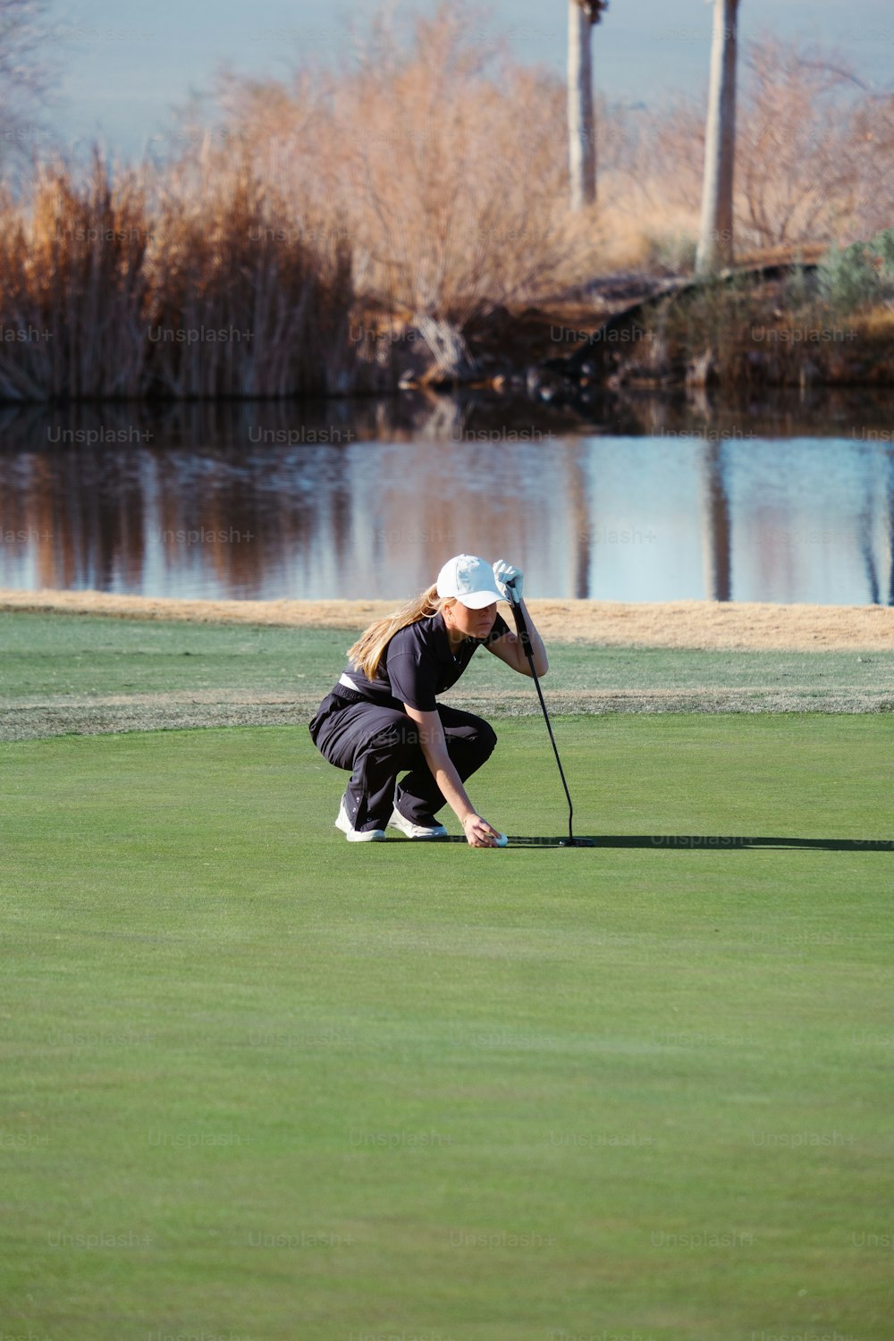 a woman kneeling down to put a golf ball on the green