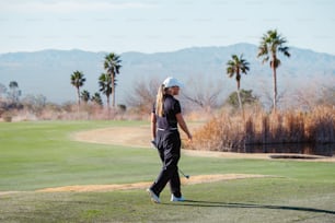 a woman walking across a green golf course