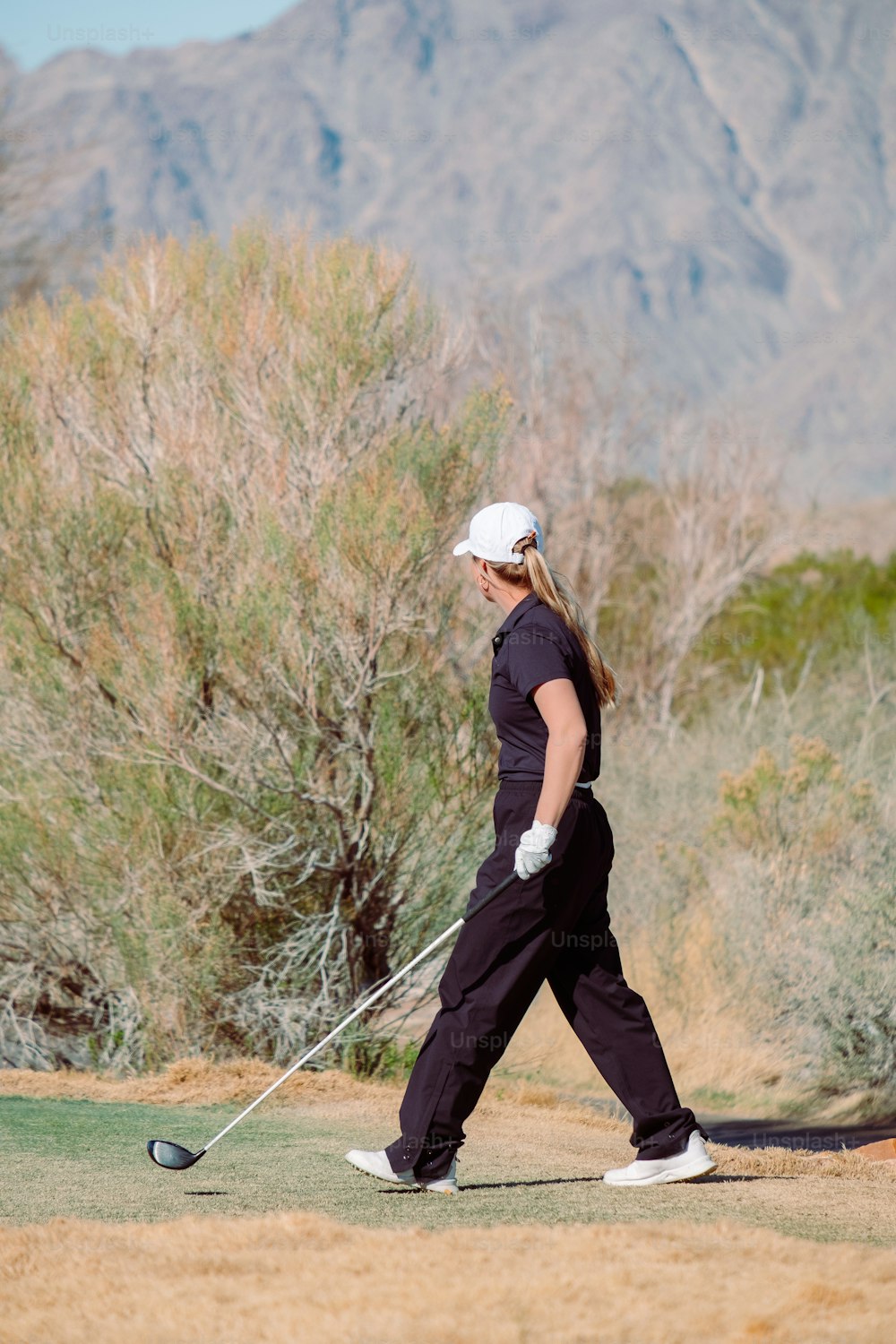 a woman is playing golf in the desert