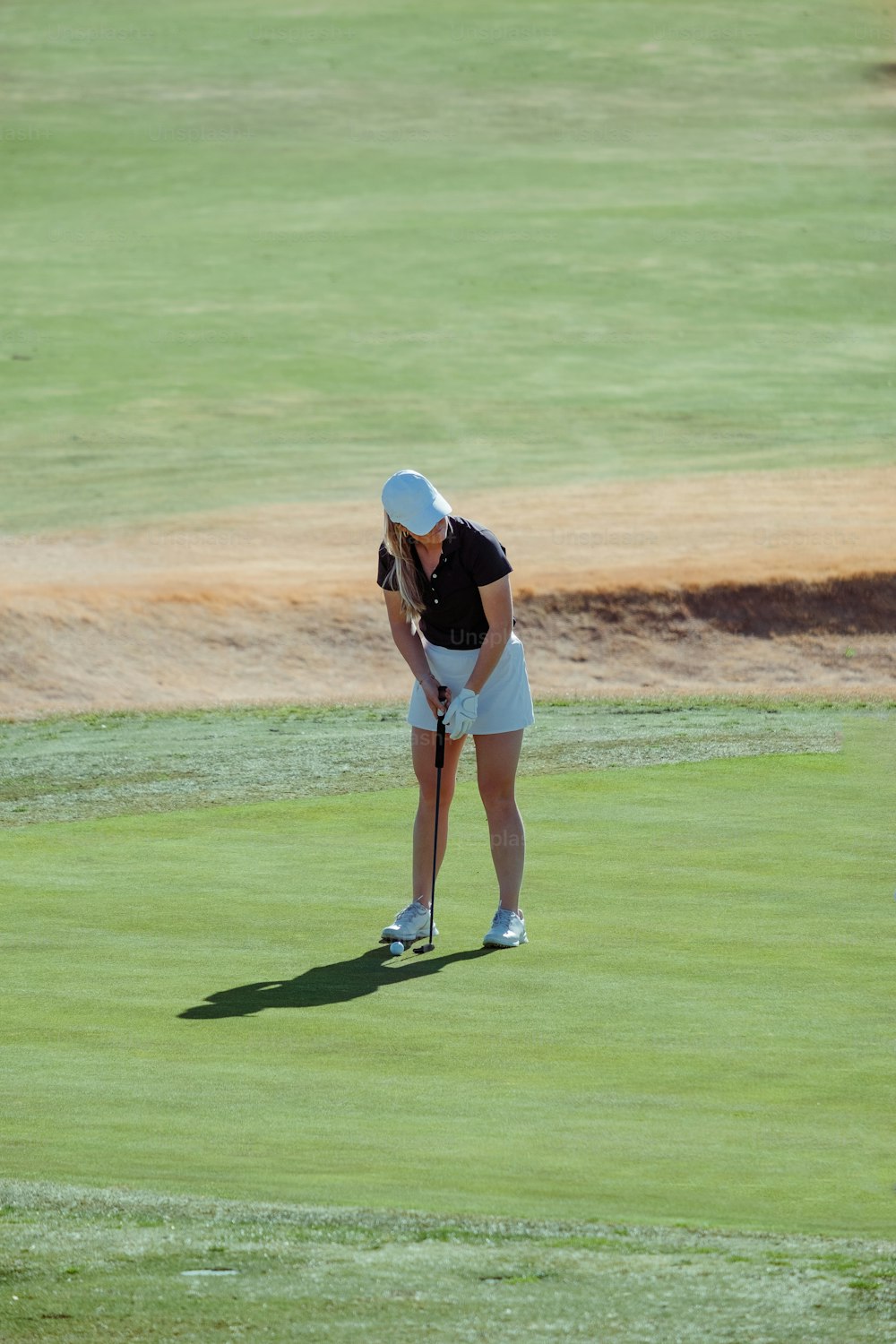 a woman in a white skirt and black shirt playing golf