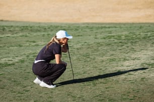 a woman kneeling down on top of a grass covered field