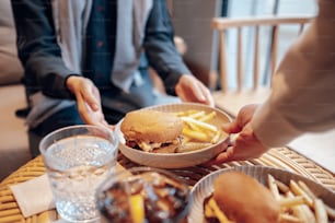 une personne tenant une assiette avec un sandwich et des frites