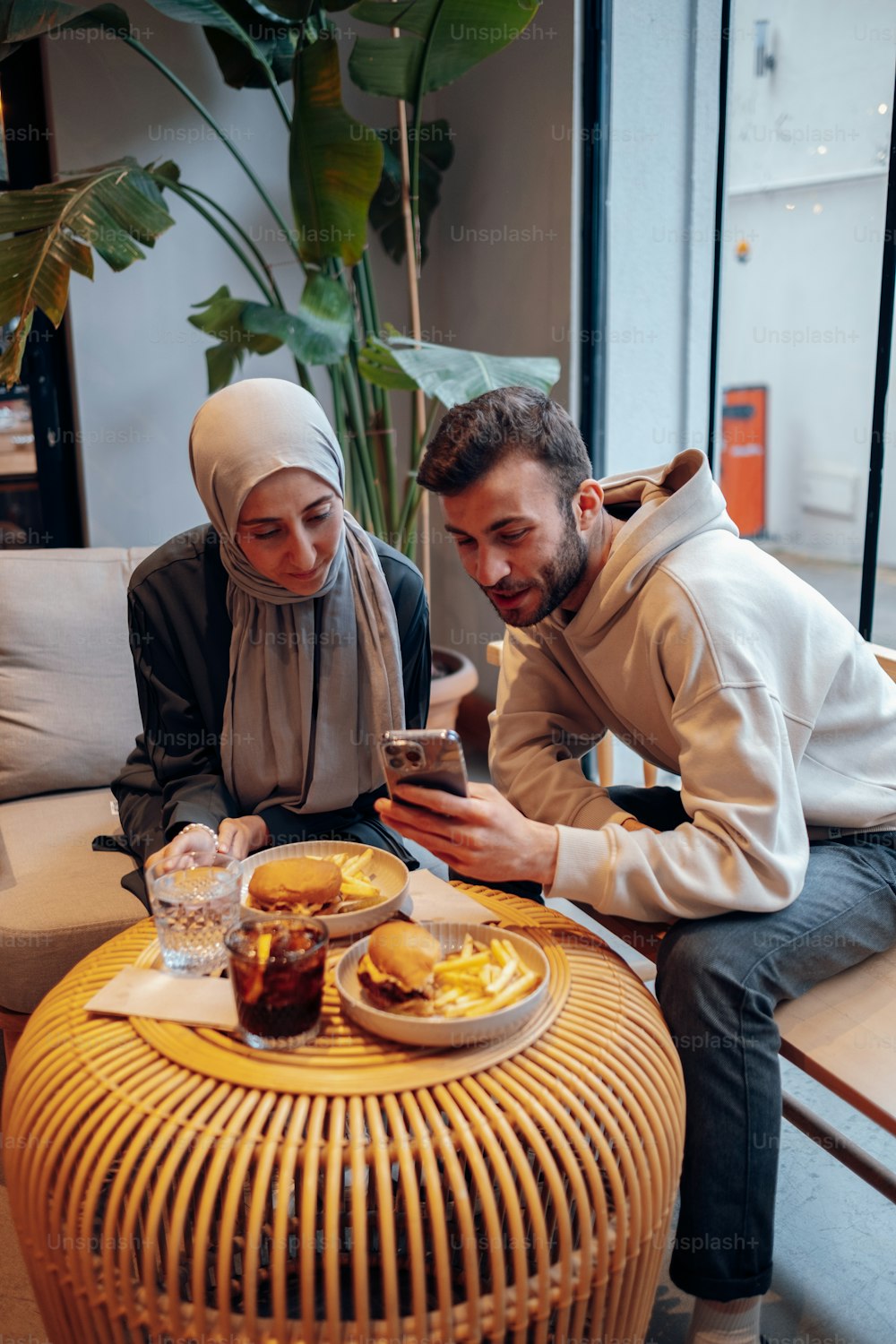 Un hombre y una mujer sentados en un sofá mirando un teléfono celular