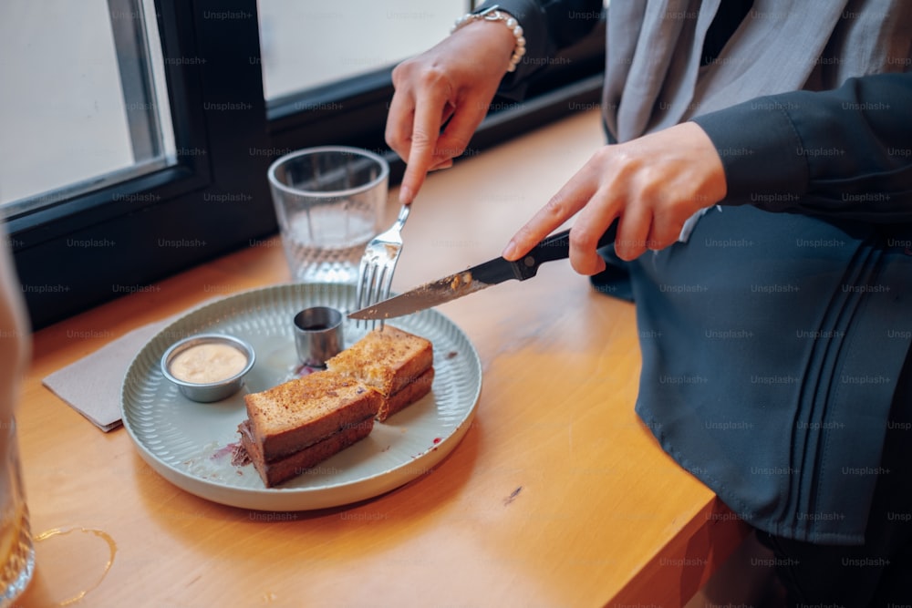 a person cutting a piece of toast on a plate