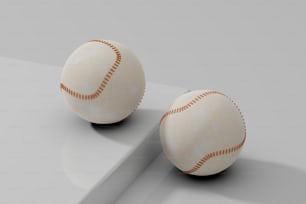two baseballs sitting on top of a white surface