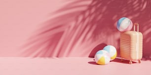 a suitcase and two beach balls on a pink background