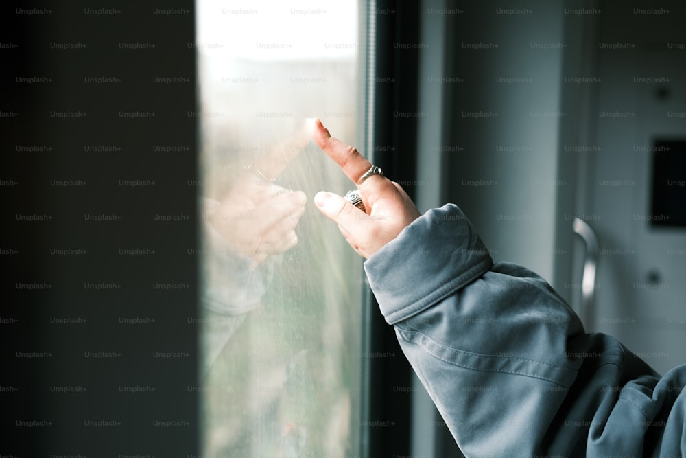 a person standing in front of a window holding a cell phone