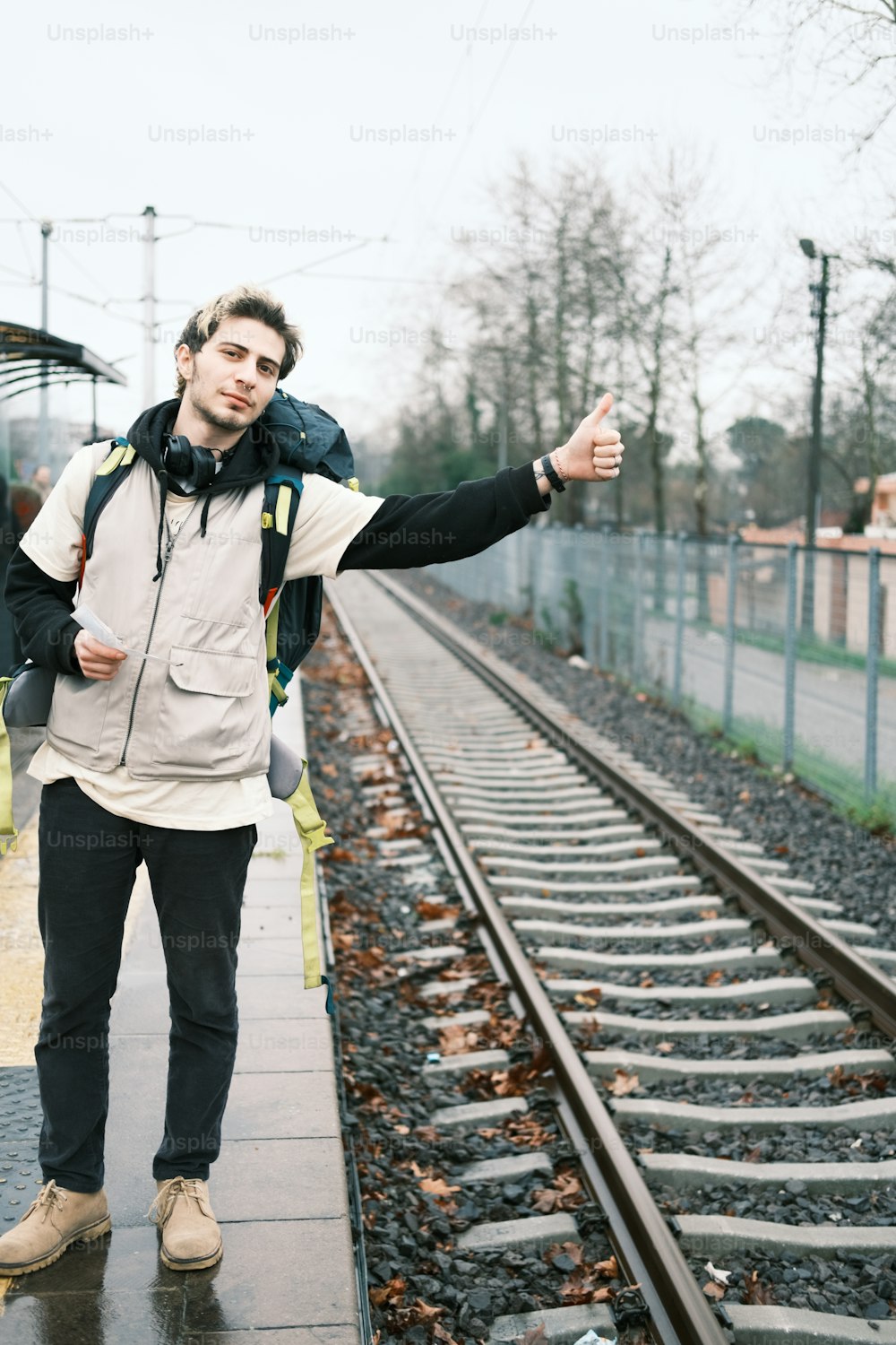 Un homme debout sur une voie ferrée levant le pouce
