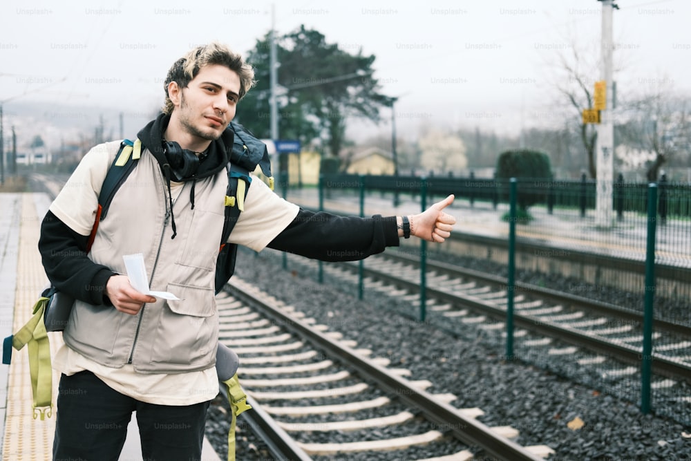 Un hombre parado en una vía de tren señalando algo