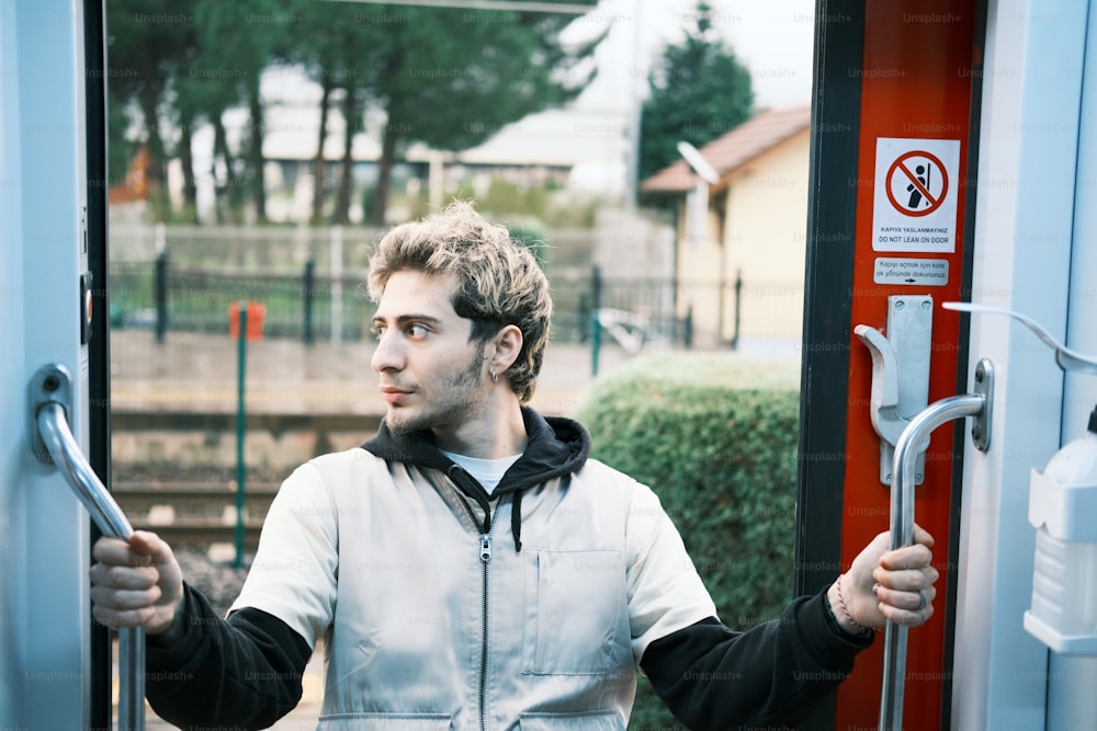 Un hombre sosteniendo la manija de una puerta en un tren