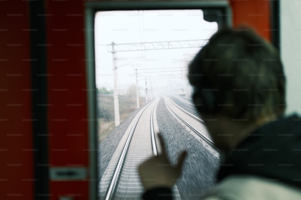 a man with headphones is looking out a train window