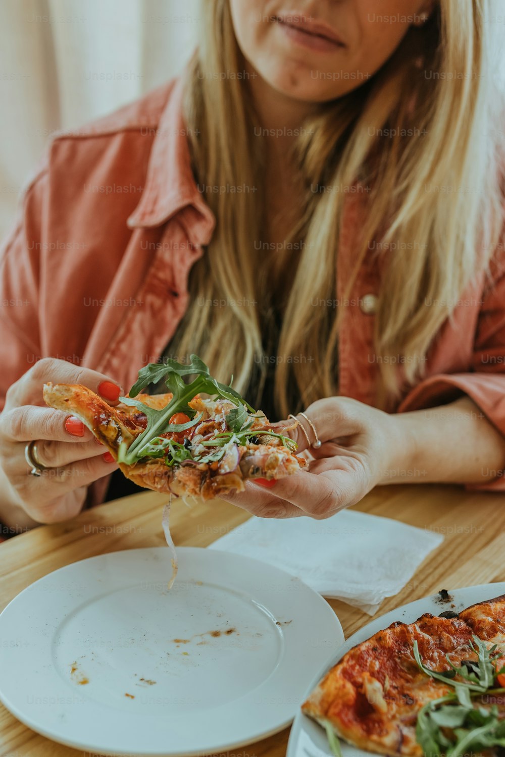 Eine Frau sitzt an einem Tisch und isst ein Stück Pizza