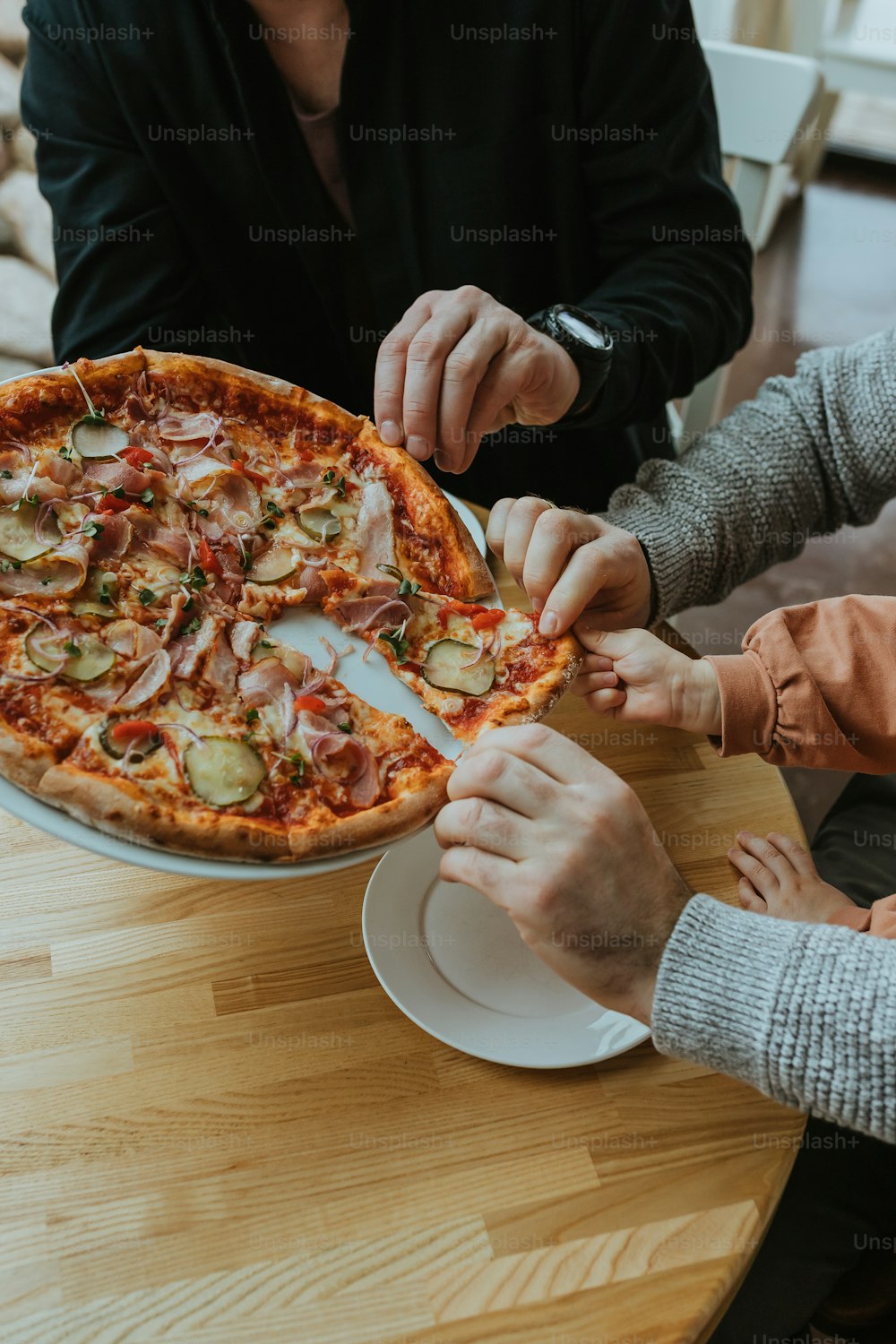 a group of people sitting around a table with a pizza