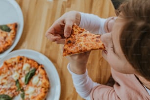 a young girl eating a slice of pizza