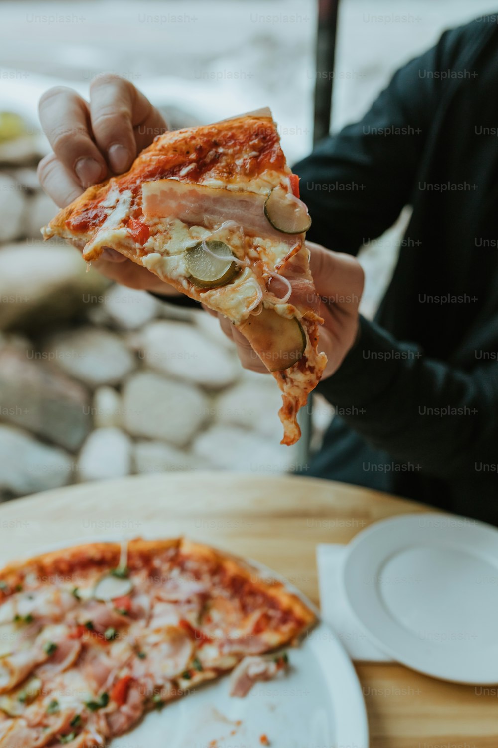 a person holding a slice of pizza in their hand
