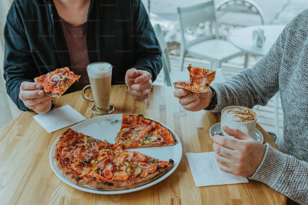 Un par de personas sentadas en una mesa con un poco de pizza