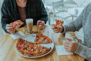 a couple of people sitting at a table with some pizza