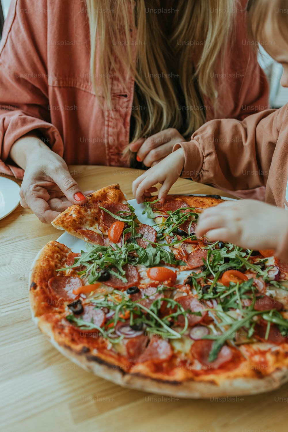 uma mulher e uma criança sentados em uma mesa com uma pizza