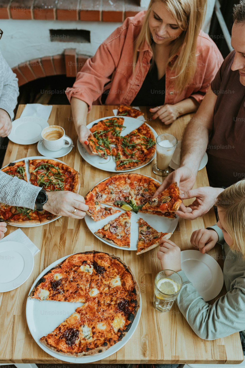 テーブルの周りに座ってピザを食べる人々のグループ