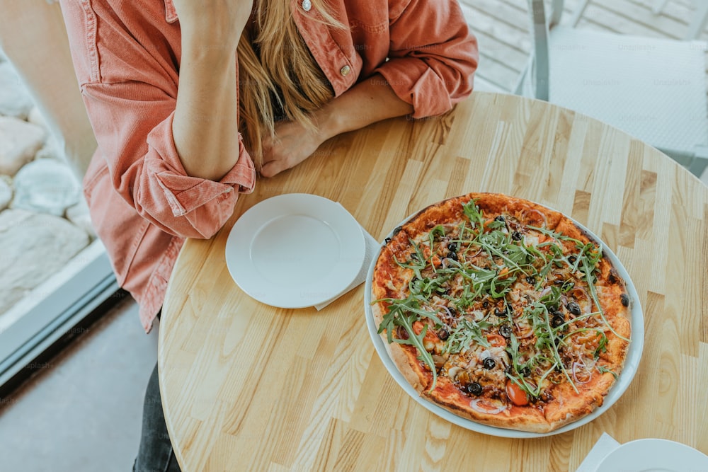 una persona seduta a un tavolo con una pizza
