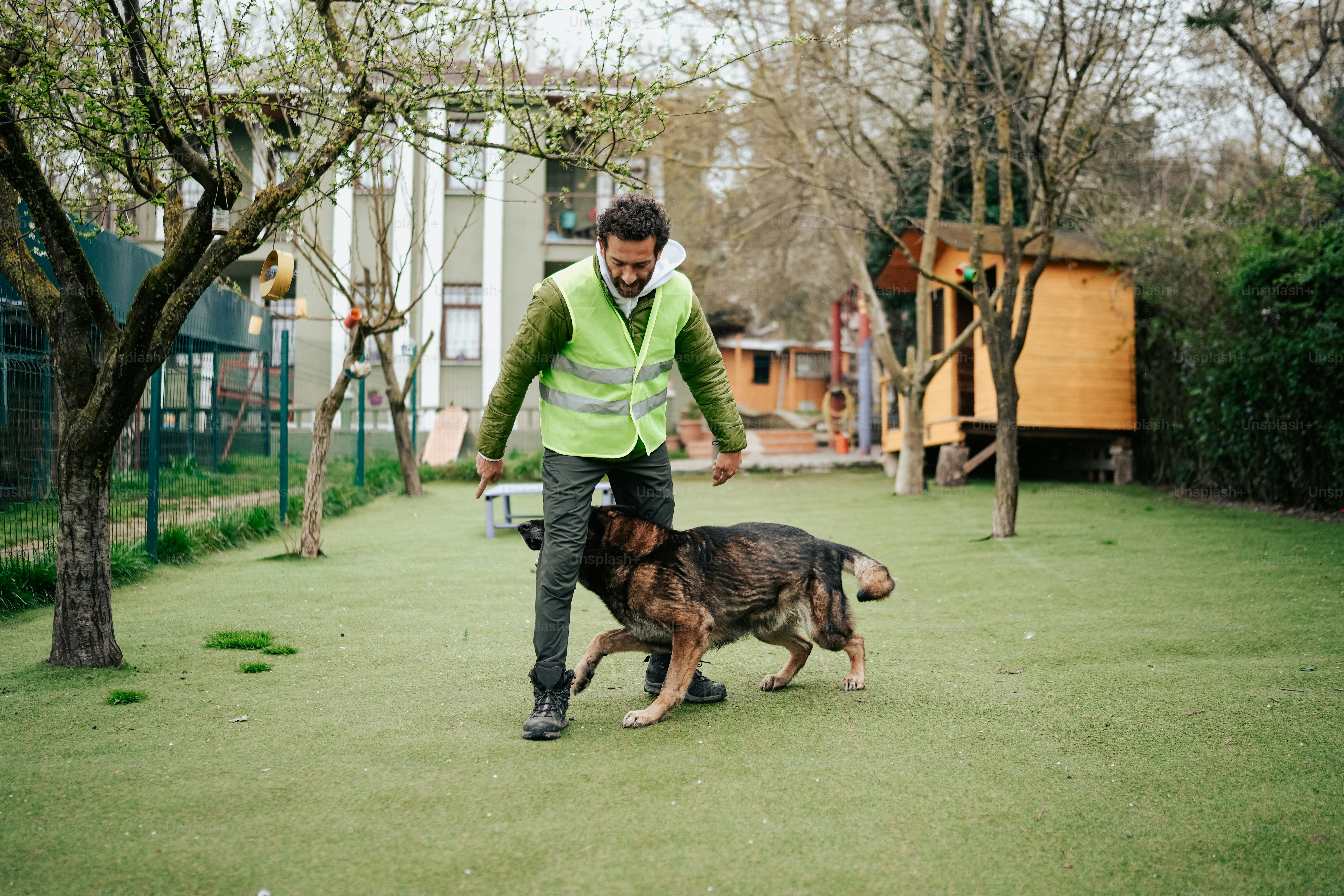 a man in a green vest is walking a dog