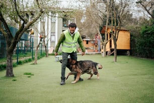 a man in a green vest is walking a dog