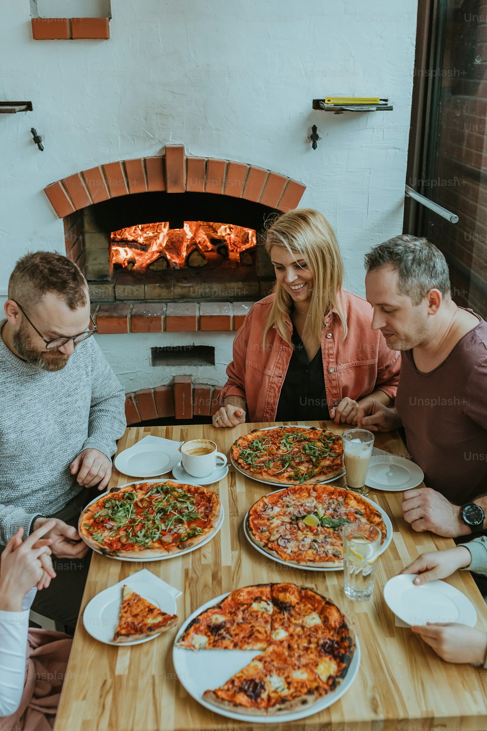 Eine Gruppe von Leuten, die um einen Tisch mit Pizza sitzen