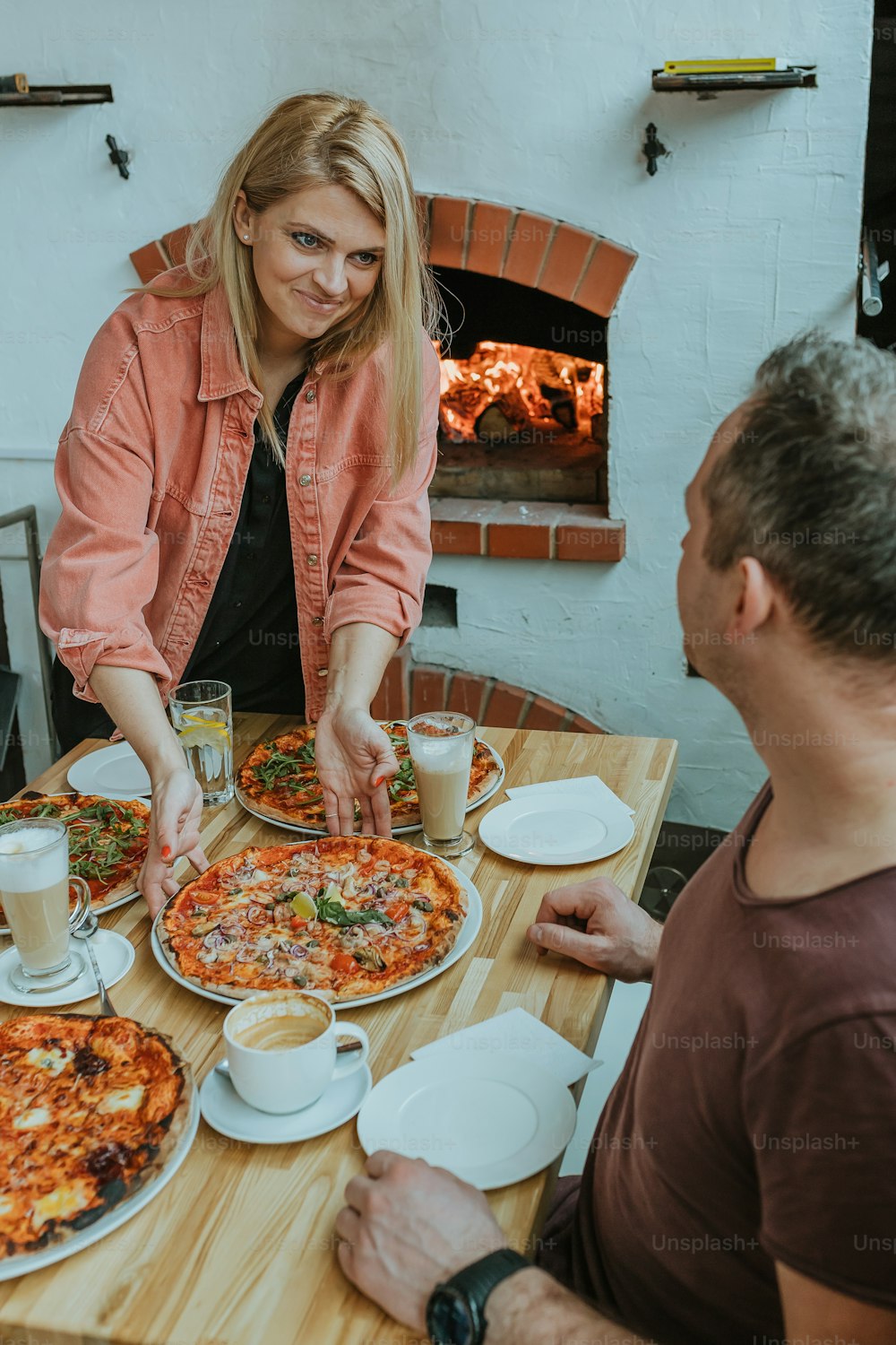 um homem e uma mulher sentados em uma mesa com pizza