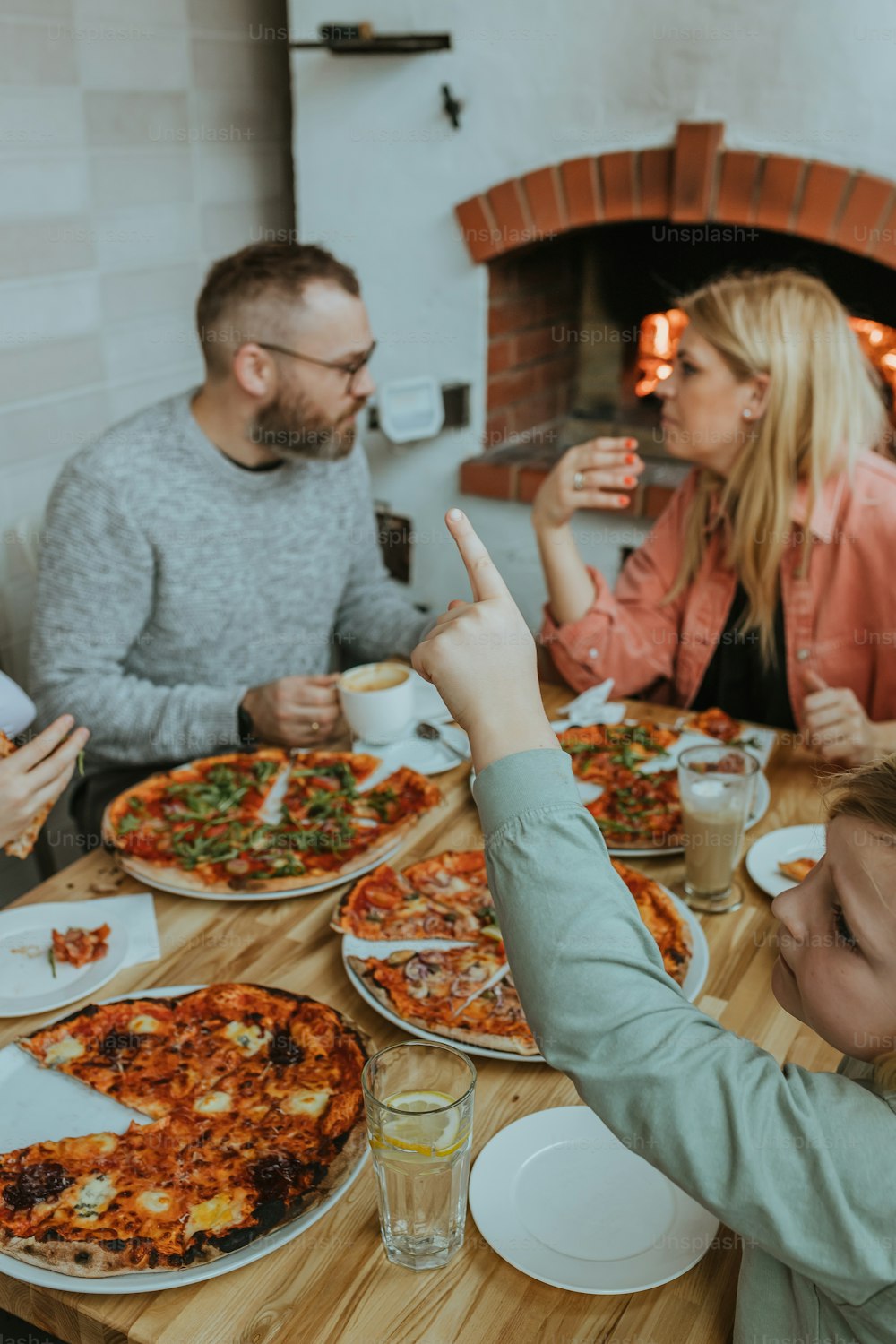 Eine Gruppe von Leuten, die um einen Tisch sitzen und Pizza essen