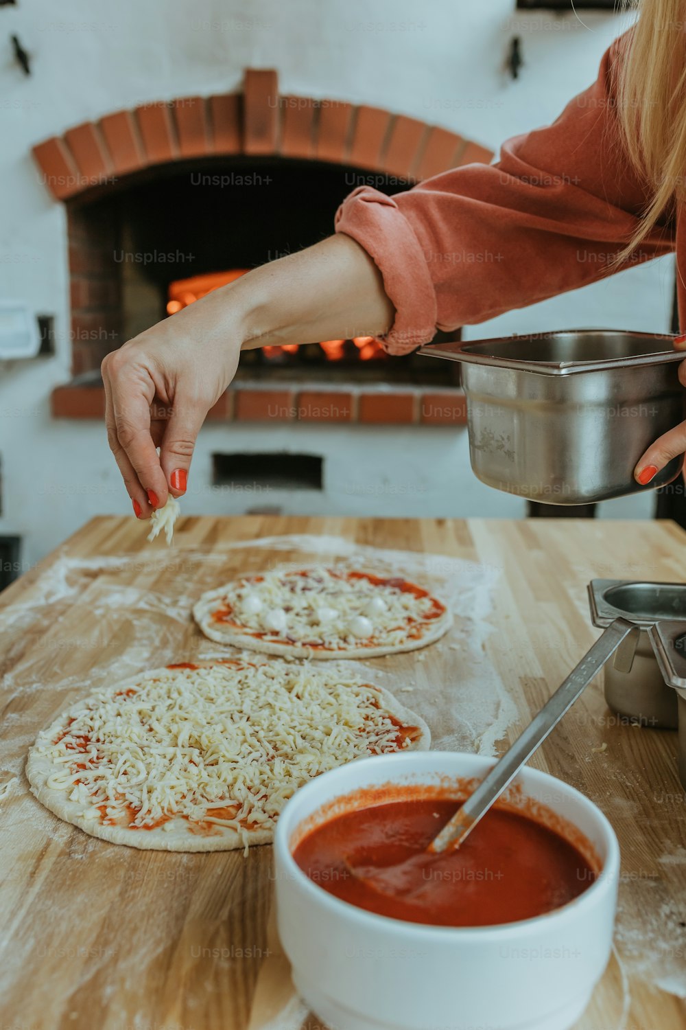 Una mujer haciendo pizzas frente a un horno