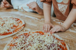 two children are making homemade pizzas on a table