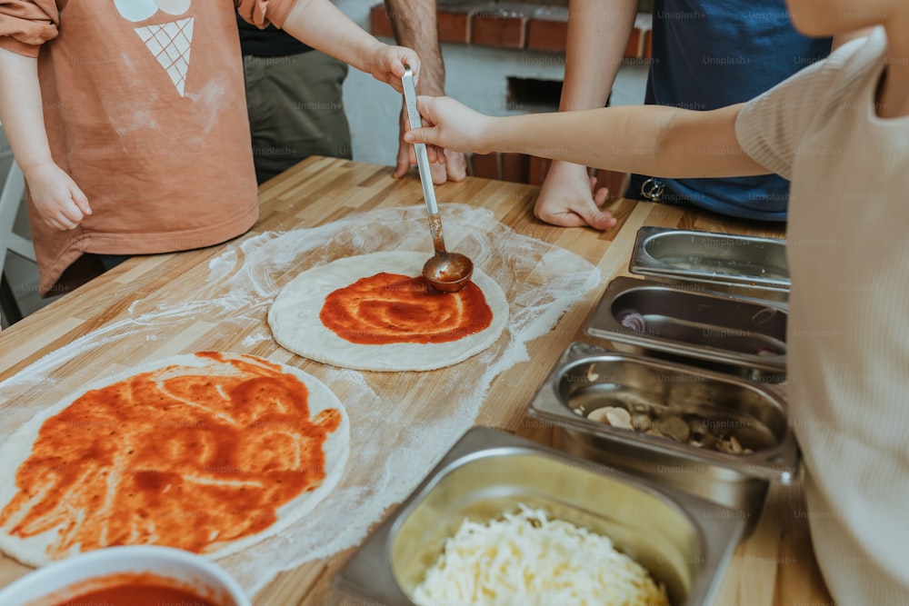 a group of people making pizzas on a table