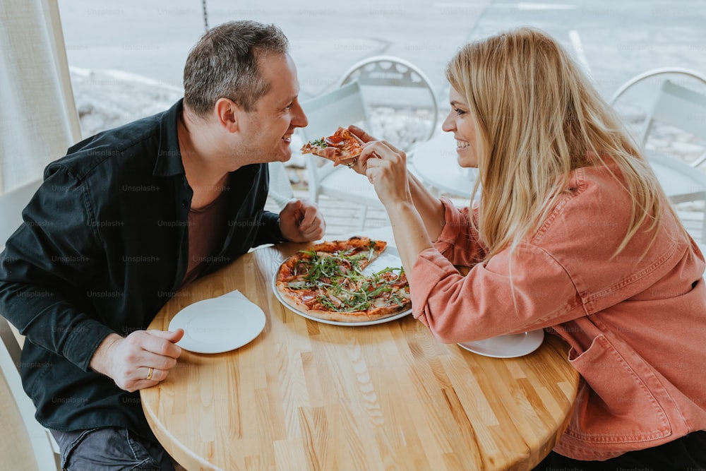 a man and a woman sitting at a table eating pizza