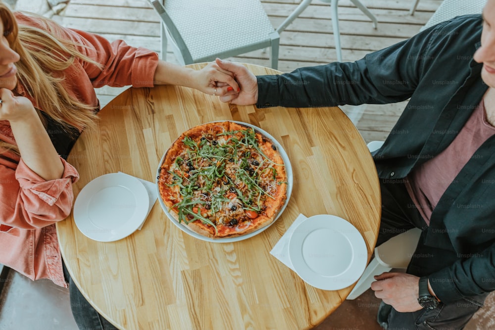 um homem e uma mulher sentados em uma mesa com uma pizza