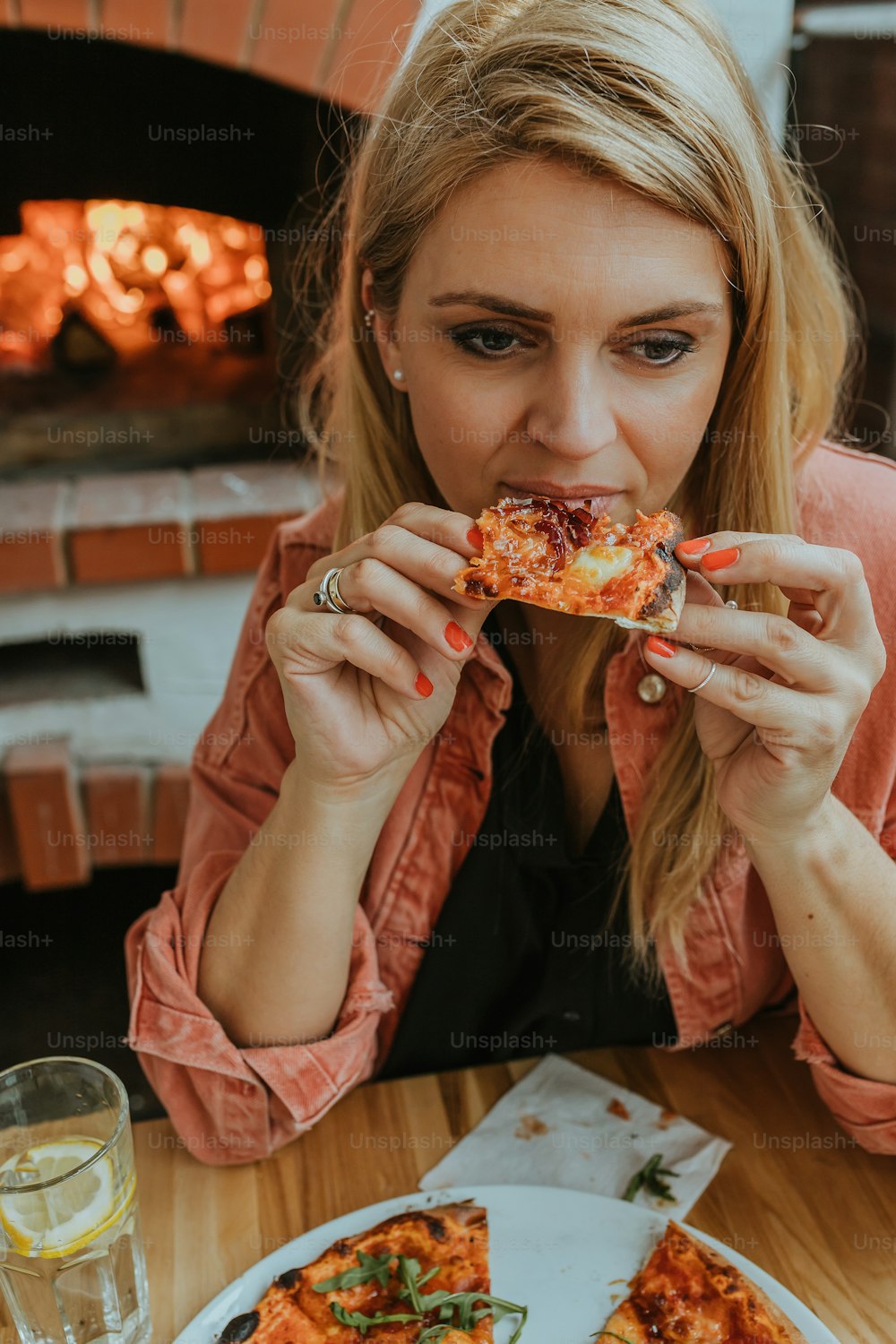 Eine Frau sitzt an einem Tisch und isst ein Stück Pizza