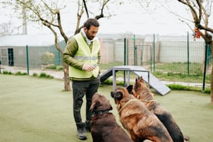 a man standing next to a group of dogs