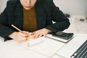 a woman sitting at a desk with a notebook and calculator