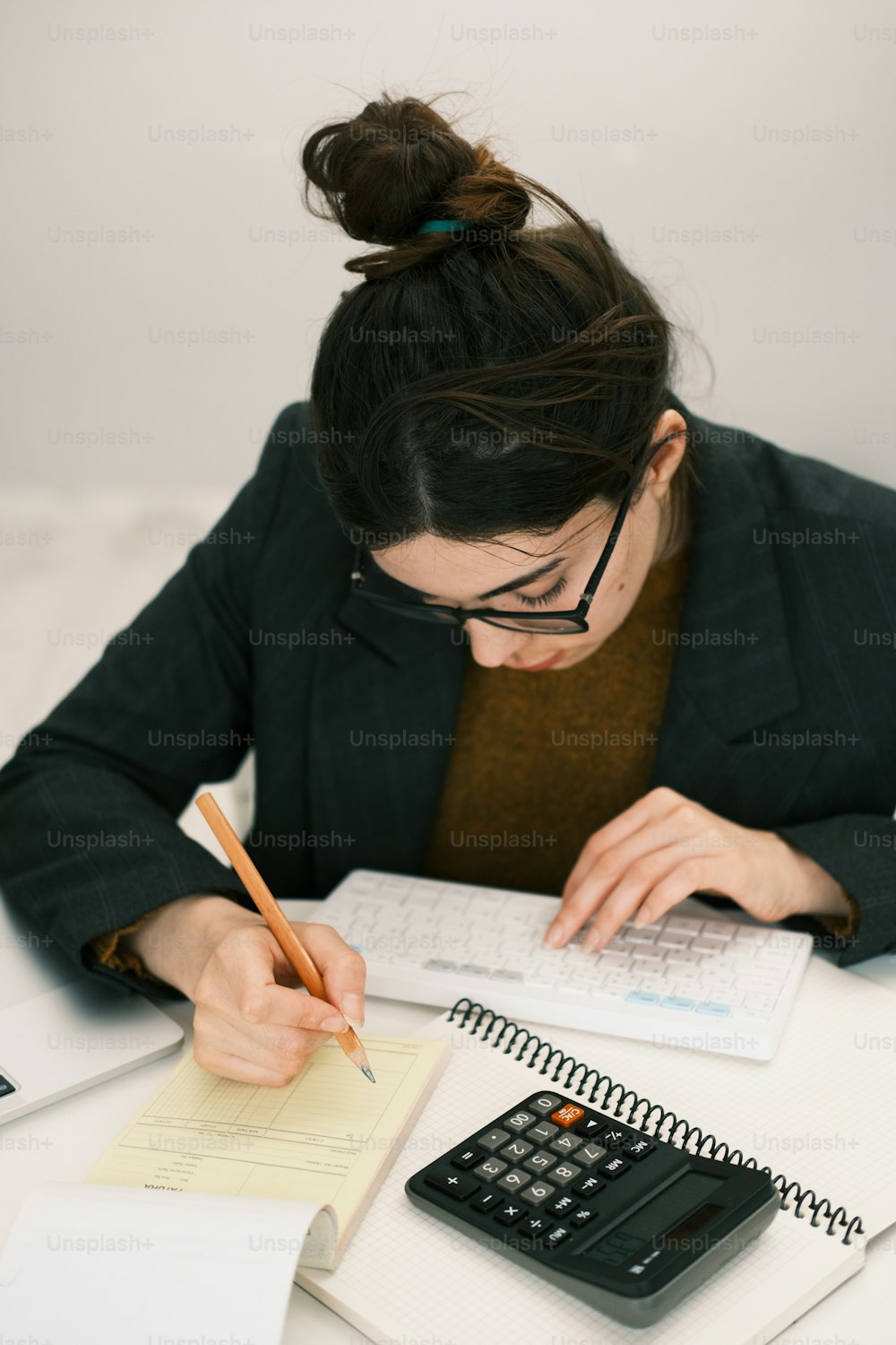 a woman sitting at a desk with a calculator and notebook