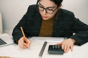 a woman sitting at a desk writing on a piece of paper