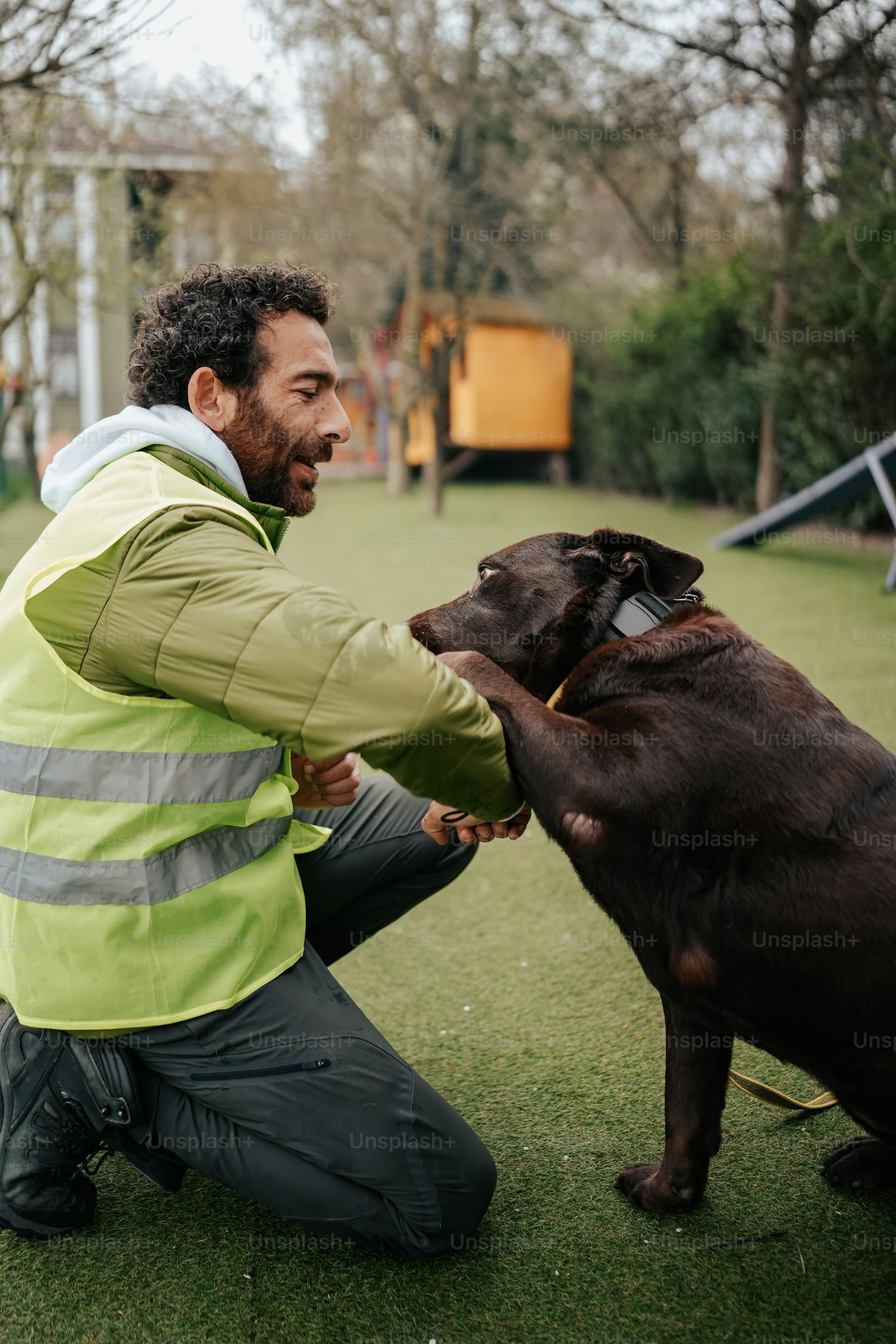 a man kneeling down next to a brown dog