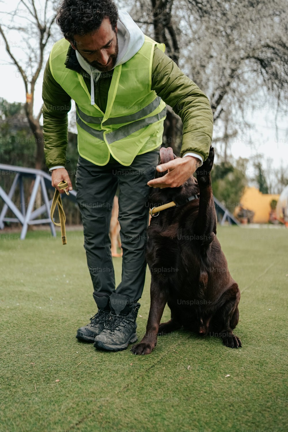 a man in a green vest is petting a brown dog