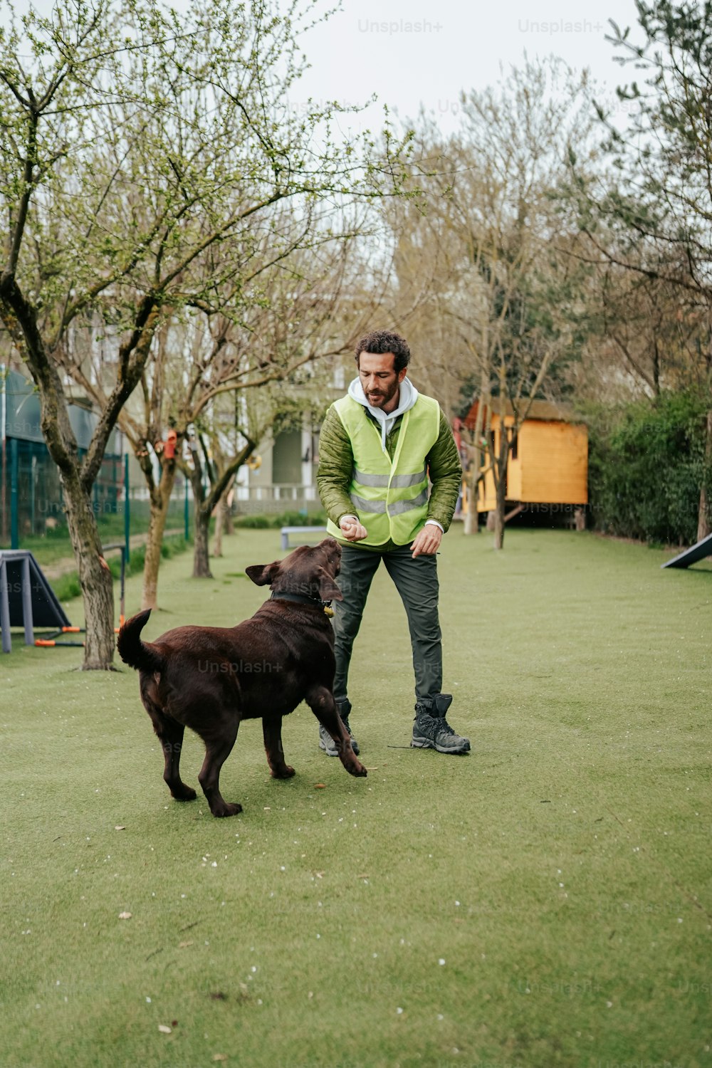 um homem brincando com um cão em um parque