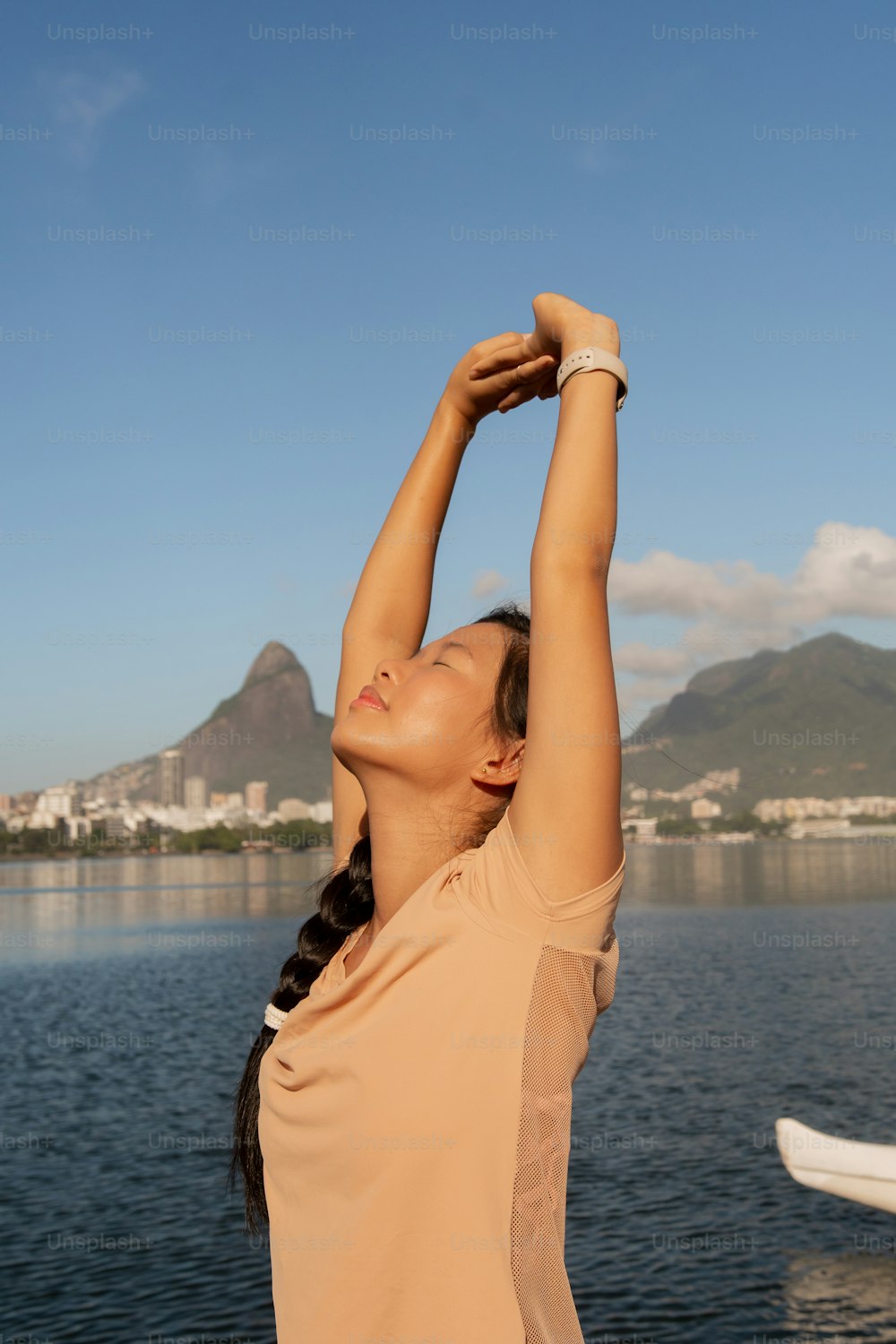 a woman stretching her arms in front of a body of water