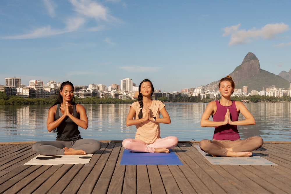 a group of women sitting on top of a wooden dock