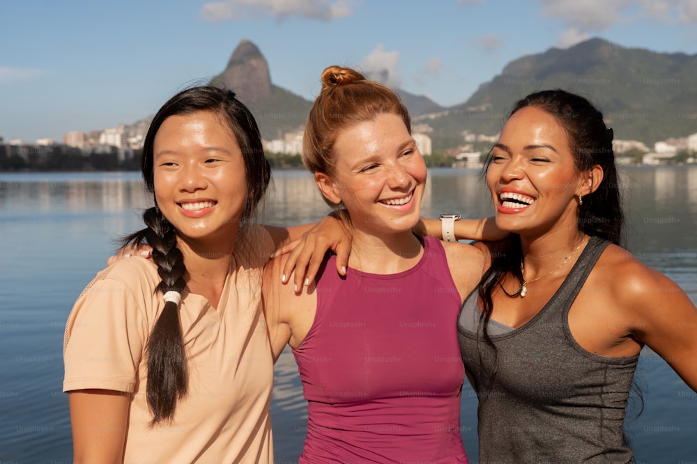 three women standing next to each other near a body of water