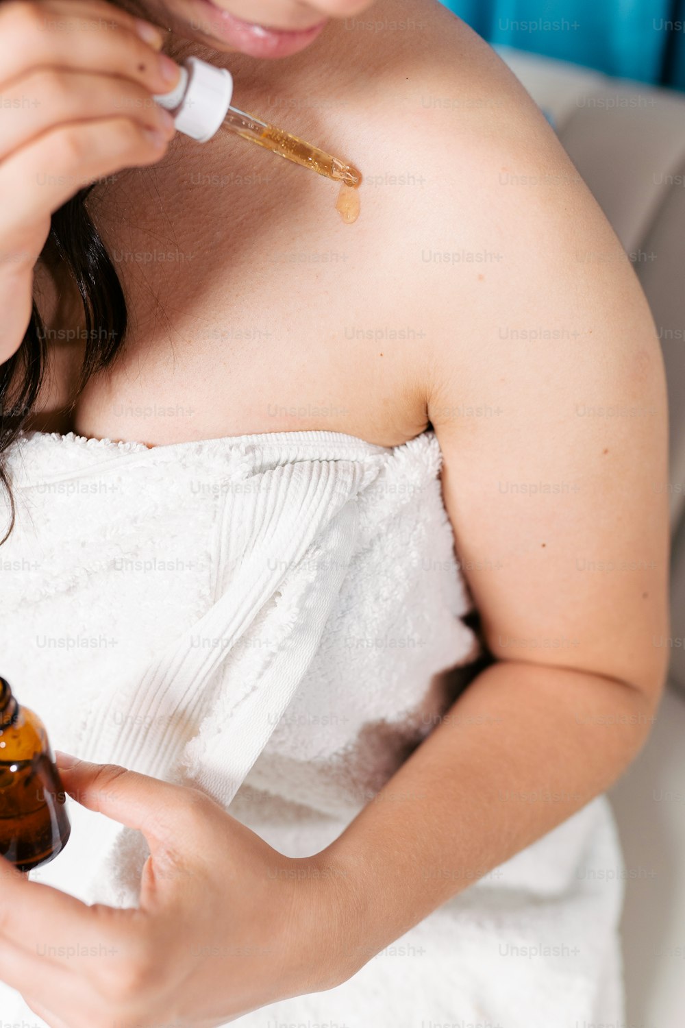 a woman in a white towel holding a bottle of essential oils